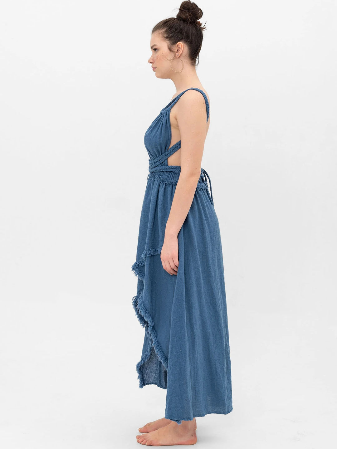 Side view of textured cotton gauze maxi dress; braided cord wraps waist, open back, raw fringe trim on