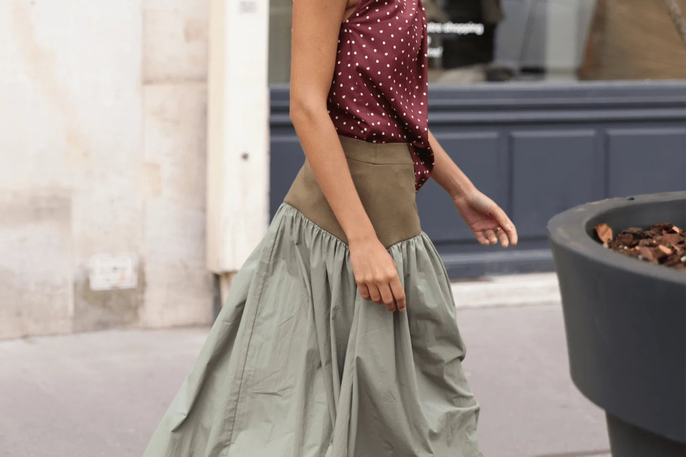 Sage green full-length maxi skirt with olive block waistband, deeply gathered lightweight skirt panel, styled with burgundy polka dot top and burgundy loafers, street setting