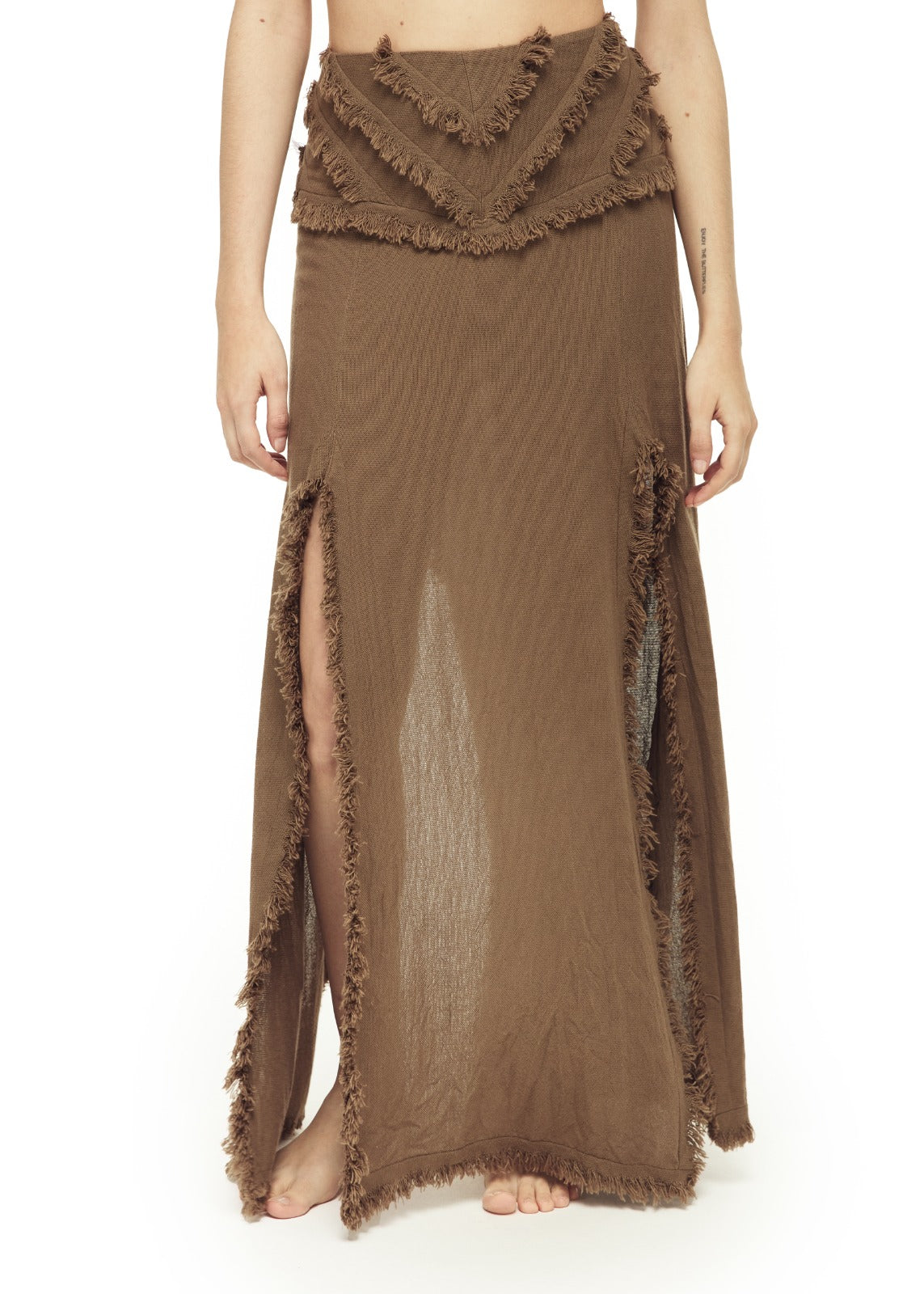 Warm brown open-weave maxi skirt with layered V-shaped fringe yoke at waist, dual fringe-trimmed side slits, and raw frayed hem. Slightly sheer fabric drapes loosely to ankle