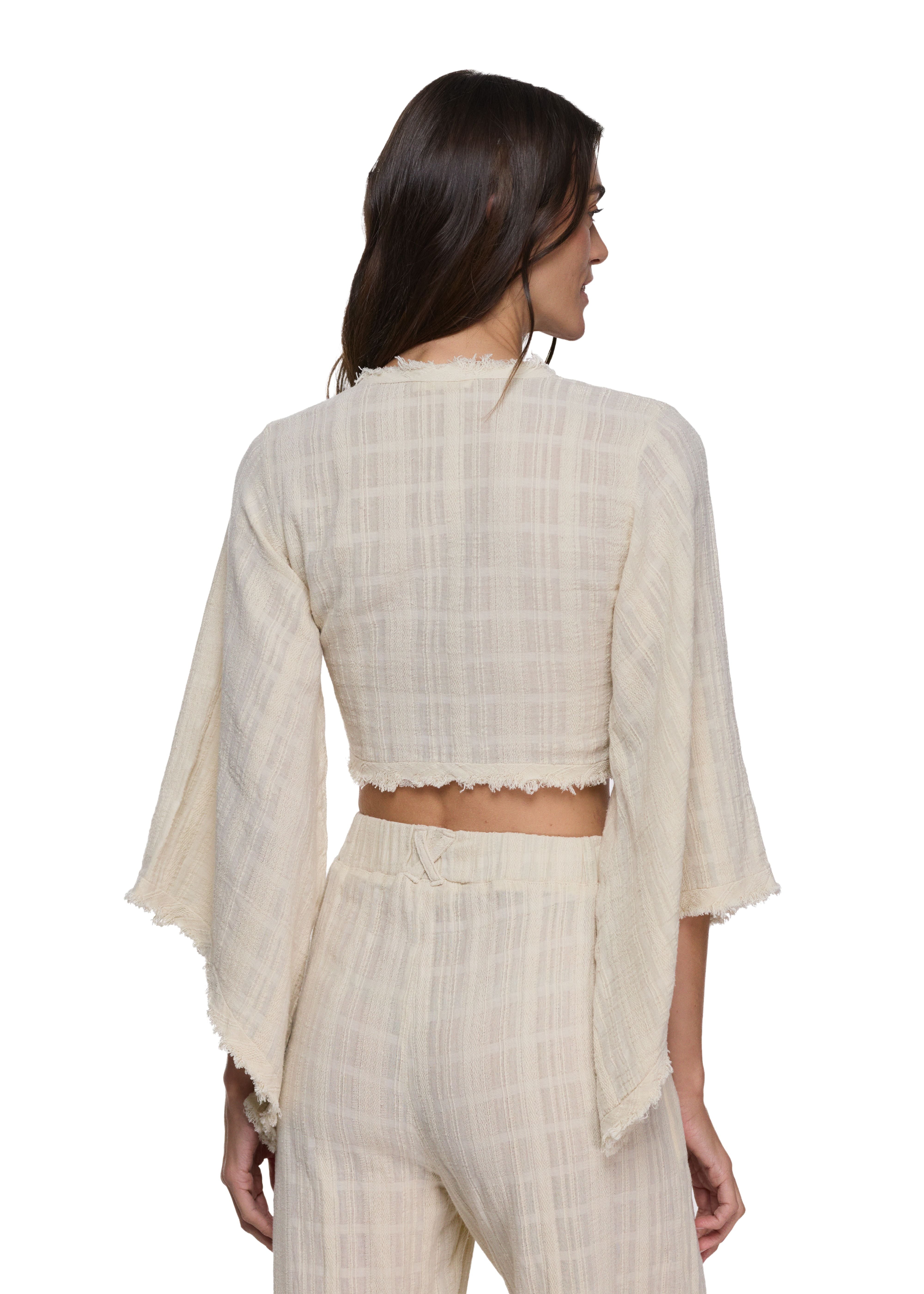Back view of cropped wrap top with dramatic flared bell sleeves and raw fringe trim hem, paired with matching