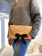 Straw clutch handbag: rectangular shape, natural straw color with black trim, flap opening
