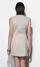 Back view of cream and near-black ticking stripe mini dress, sleeveless, structured canvas fabric, angled skirt panels, fitted waist, gold bangle bracelet detail.